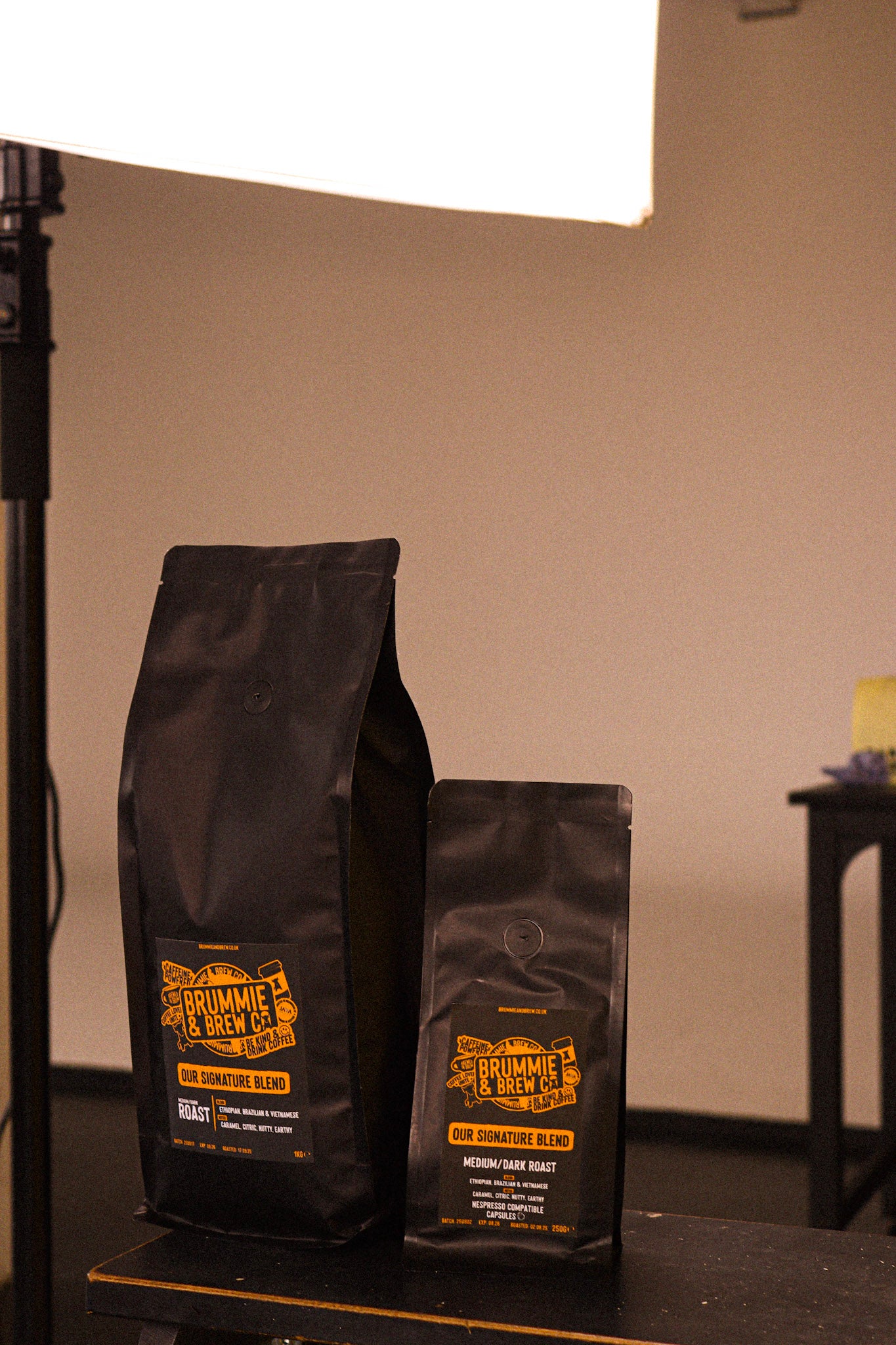 Two black bags of speciality coffee in 1kg and 250g on a black surface
