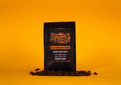 Coffee bag with branding on a yellow background surrounded by coffee beans at the bottom